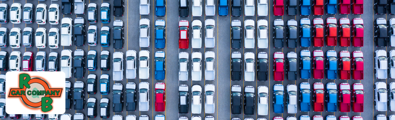An aerial view of rows of cars parked on a lot with different colors makes